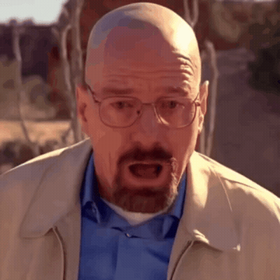 A Bald Man With Glasses And A Beard Is Wearing A Blue Shirt And A Tan Jacket GIF