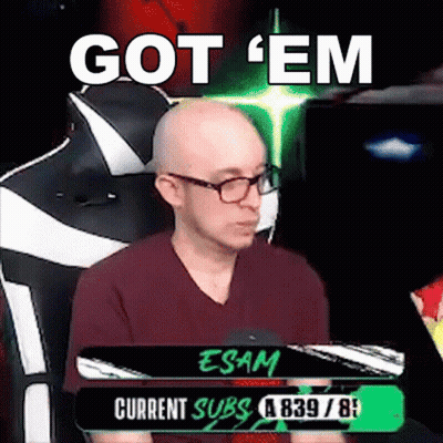 A Bald Man With Glasses Is Sitting In A Chair With The Words `` Got 'Em '' Written On The Screen . GIF
