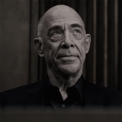 A Bald Man With His Eyes Closed And A Black Shirt GIF