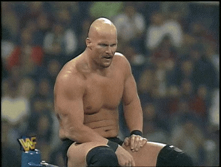 A Bald Wrestler Without A Shirt Is Sitting In A Wrestling Ring . GIF