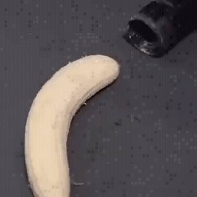A Banana Is Being Peeled By A Black Knife On A Black Surface . GIF