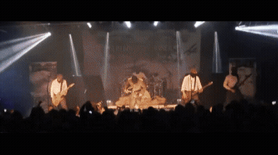 A Band Is Playing On Stage In Front Of A Crowd GIF