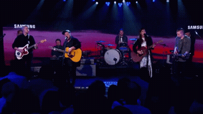 A Band Performs On Stage In Front Of A Samsung Banner GIF