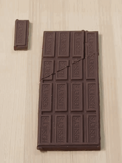 A Bar Of Hershey 'S Chocolate Is Broken In Half On A Table GIF