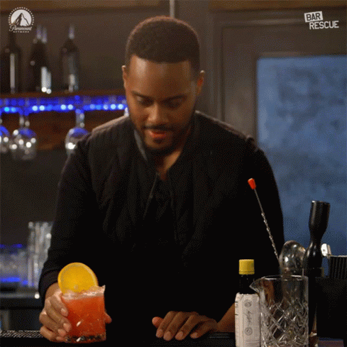 A Bartender Prepares A Drink With A Paramount Logo On The Wall Behind Him GIF