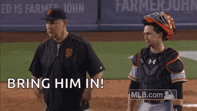 A Baseball Coach And Catcher Are Standing On A Baseball Field And The Coach Is Saying Bring Him In . GIF