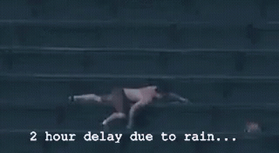 A Baseball Game Is Being Played In The Rain And The Scoreboard Says 2 Hour Delay Due To Rain GIF