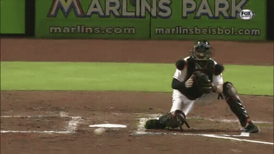 A Baseball Player Catches A Ball In Front Of A Sign That Says Marlins Park GIF