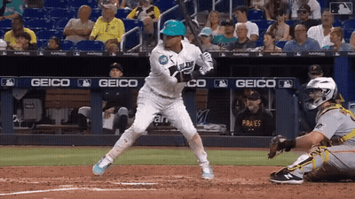 A Baseball Player Getting Ready To Hit The Ball In Front Of A Banner That Says Geico GIF