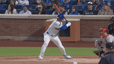 A Baseball Player Getting Ready To Swing At A Pitch While A Fan Wearing A Brtn Shirt Watches GIF