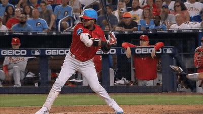 A Baseball Player Getting Ready To Swing At A Pitch With A Geico Banner Behind Him GIF