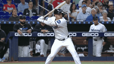 A Baseball Player Getting Ready To Swing At A Pitch With A Geico Banner In The Background GIF