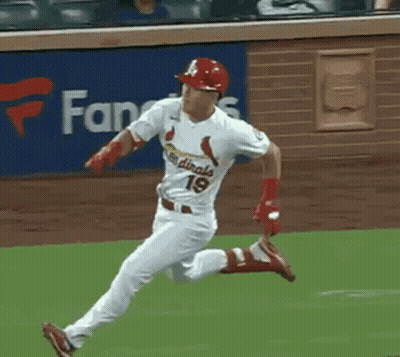 A Baseball Player In A Cardinals Uniform Is Running On A Field . GIF