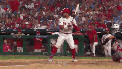 A Baseball Player In A Phillies Uniform Is Swinging A Bat At A Ball . GIF