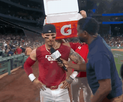 A Baseball Player Is Being Interviewed By A Reporter While Holding A Gatorade Cooler On His Head GIF