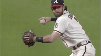 A Baseball Player Is Catching A Ball On A Field While Wearing A Hat And Glove . GIF