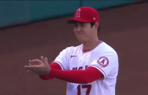 A Baseball Player Is Clapping His Hands While Wearing A Red Hat And White Jersey . GIF