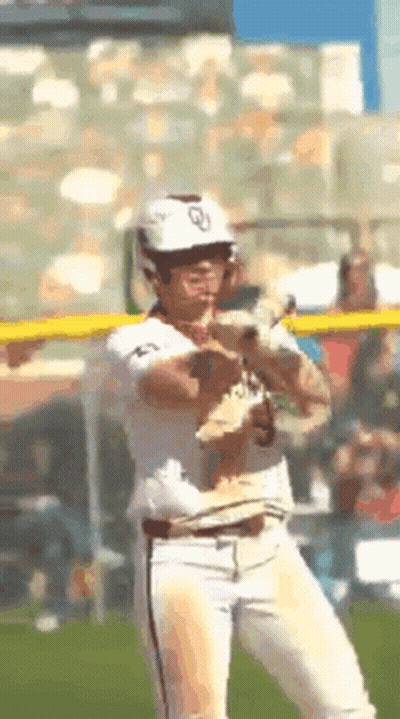 A Baseball Player Is Holding A Small Dog In His Hand GIF