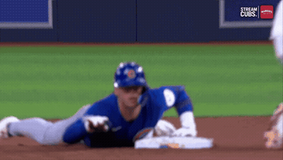 A Baseball Player Is Laying On The Ground On The Field . GIF