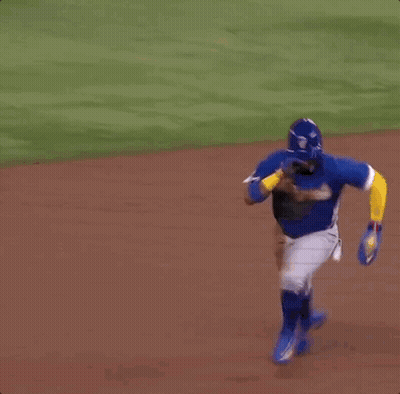 A Baseball Player Is Laying On The Ground While A Referee Watches . GIF
