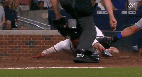 A Baseball Player Is Laying On The Ground While A Referee Watches GIF