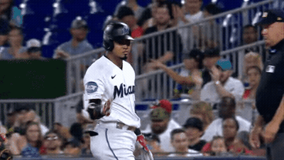 A Baseball Player Is Running Towards The Dugout While A Referee Watches . GIF