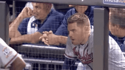 A Baseball Player Is Shaking Hands With A Fan While Sitting In The Dugout . GIF