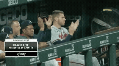 A Baseball Player Is Sitting In The Dugout Applauding His Team . GIF