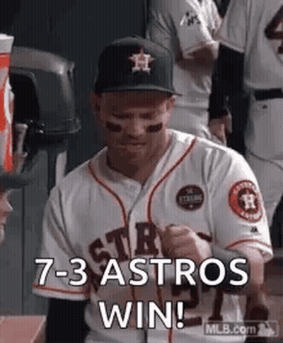 A Baseball Player Is Sitting In The Dugout With His Fist In The Air And Says `` 7- 3 Astros Win '' . GIF