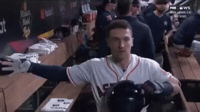 A Baseball Player Is Standing In A Dugout With His Arms Outstretched And Holding A Helmet . GIF