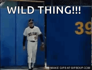 A Baseball Player Is Standing In Front Of A Blue Wall With The Words `` Wild Thing '' Written On It . GIF