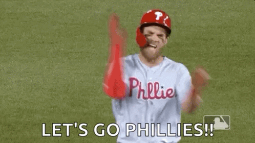 A Baseball Player Is Standing On A Field With His Arms In The Air And Saying `` Let 'S Go Phillies '' . GIF