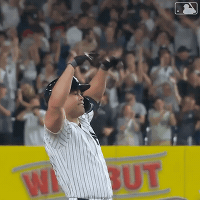 A Baseball Player Is Standing On The Field With His Arms In The Air GIF