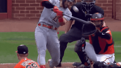 A Baseball Player Is Swinging A Bat At A Ball While The Catcher Watches GIF