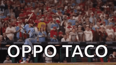 A Baseball Player Is Swinging At A Ball In Front Of A Crowd . GIF