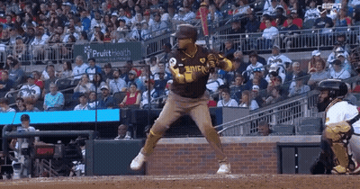 A Baseball Player Is Swinging At A Ball In Front Of A Crowd . GIF