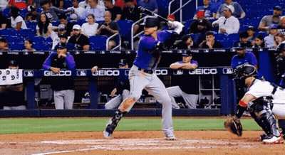 A Baseball Player Is Swinging At A Ball In Front Of A Geico Sign GIF