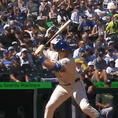 A Baseball Player Is Swinging At A Pitch In Front Of A Seattle Mariners Banner GIF