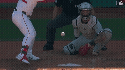 A Baseball Player Is Swinging His Bat At A Ball While The Catcher Watches GIF