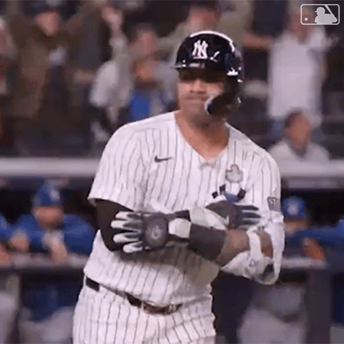 A Baseball Player Is Swinging His Bat At A Ball While Wearing A Helmet And Sunglasses . GIF