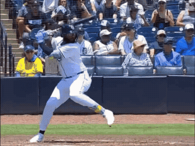 A Baseball Player Is Swinging His Bat At A Ball With A Crowd Watching GIF