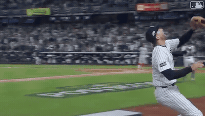 A Baseball Player Is Throwing A Ball In A Stadium With A Sign That Says ' Coca Cola ' On It GIF
