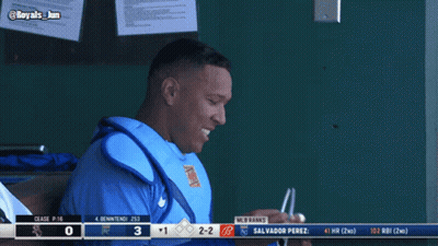 A Baseball Player Sitting In The Dugout With A Scoreboard Behind Him That Says Mlb Ranks GIF