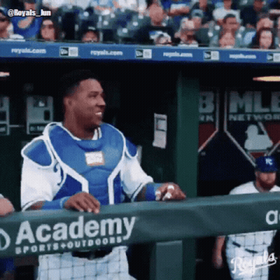 A Baseball Player Stands Behind A Fence That Says Academy Sports & Outdoors GIF