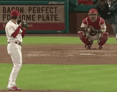 A Baseball Player Stands In Front Of A Bacon Perfect Home Plate Sign GIF