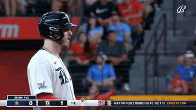 A Baseball Player Stands In Front Of A Scoreboard That Says Rangers.com GIF
