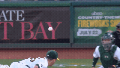 A Baseball Player Throws The Ball In Front Of A Sign That Says Fireworks GIF