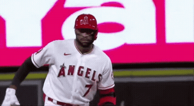 A Baseball Player Wearing A Angels Jersey Is Standing In Front Of A Large Screen . GIF