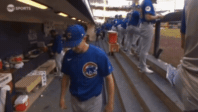 A Baseball Player Wearing A Blue Cubs Shirt Walks Down The Stairs GIF
