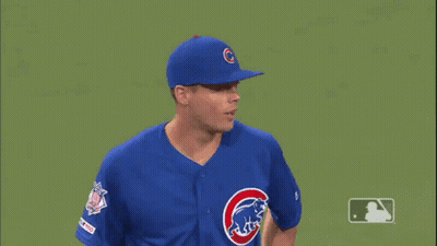 A Baseball Player Wearing A Blue Cubs Uniform Is Standing On A Green Field . GIF